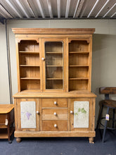 Load image into Gallery viewer, A characterful vintage pine Welsh dresser with genuine patina reflecting its age. Structurally solid and fully functional, this piece shows honest wear through surface marks that add to its authentic charm. The practical design features three shelves above two single cupboards, plus three dovetail-jointed drawers —ideal for substantial storage needs. Thoughtfully designed to separate into two sections for convenient transport and placement.

Delivery Available

Overall Dimensions

152cm wide x 46cm deep x 2
