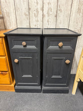 Load image into Gallery viewer, A matching pair of tall, narrow bedside units in black. Each features one drawer and one cupboard for practical storage. Structurally sound with light wear consistent with pre-loved furniture. Ideal for refreshing with paint as part of an up-cycle project, or use as-is for authentic vintage character.

Delivery Available

Overall Dimensions

35cm wide x 45cm deep x 77cm high

