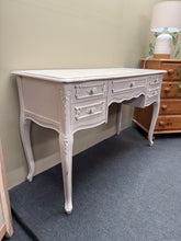 Load image into Gallery viewer, This elegant white distressed dressing table brings French provincial charm to any bedroom. Structurally sound and well-maintained, it features five generous drawers—four short and one long—providing ample storage for cosmetics, jewellery, and accessories. The distressed finish adds authentic vintage character while the spacious top offers room for a mirror and daily essentials.

Delivery Available

Overall Dimensions

121cm wide x 45cm deep x 75cm high

