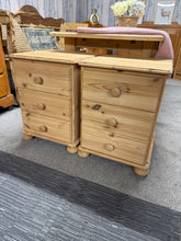 Load image into Gallery viewer, A matching pair of solid pine bedside tables, stripped to natural wood. Each unit features three short drawers providing practical storage for essentials. These pieces are structurally robust and well-maintained, though the bare wood will benefit from wax or oil treatment to protect the surface. Ideal for those seeking authentic vintage character with functional design.

Delivery Available

Overall Dimensions

45cm wide x 44cm deep x 61cm high&nbsp;

