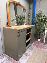 Load image into Gallery viewer, A charming oak sideboard finished in soft sage green, with natural oak top and shelves. Two cupboards with single shelves flank a central open shelving section featuring two display shelves. Structurally sound and in good condition with minor cosmetic marks consistent with age. A versatile piece that brings warmth and character to any room.

Delivery Available

Overall Dimensions

137cm wide x 51cm deep x 86.5cm high

