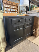 Load image into Gallery viewer, This striking oak sideboard showcases a sophisticated 'Black Jack' finish by Frenchic, delivering timeless elegance to any dining room or hallway. Built with solid construction, it features two dovetail-jointed drawers and two single cupboards—perfect for storing tableware, linens, or home essentials. Structurally sound with minor surface marks consistent with its character, this statement piece blends vintage charm with modern styling. Ideal for those seeking quality vintage furniture with authentic patina
