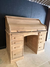 Load image into Gallery viewer, A beautiful solid oak roll top desk, stripped back to reveal its natural character. Structurally sound with excellent storage—eight dovetail-jointed drawers beneath the writing surface provide ample workspace organisation. The desk disassembles for convenient transport and storage. Please note: The piece has been restored to bare wood and would benefit from a protective wax finish. The roll top mechanism requires some adjustment and may need gentle persuasion to close smoothly. Ideal for those who appreciat

