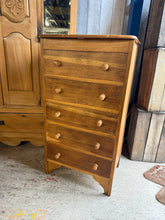 Load image into Gallery viewer, Discover the timeless appeal of this Mid Century Tall Boy, a well-preserved piece featuring solid construction and authentic character. The chest showcases five spacious dovetail-jointed drawers topped with an integrated vanity unit and mirror—perfect for bedroom storage and grooming. Light wear from years of use adds to its vintage charm, while the sturdy craftsmanship ensures reliable everyday functionality. An excellent choice for those seeking genuine mid-century design with practical storage solutions.
