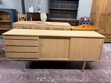 Load image into Gallery viewer, This beautiful teak sideboard has been fully restored to its original, natural finish. Minor marks where the veneer has slightly lifted enhance its unique character. It offers plenty of storage space with four spacious drawers and a double cupboard concealed behind a sliding door. It may benefit from a coat of wax for protection.

Overall Dimensions

182cm wide x 44cm deep x 80cm high

DELIVERY AVAILABLE      

For our other items see our website https://fossewayfurniture.co.uk

collection from our shop at 
