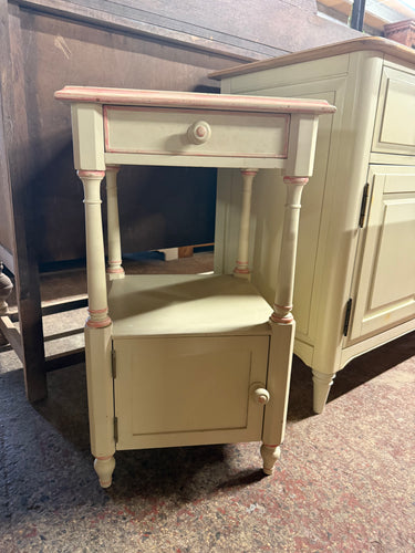 This delightful cream and pink tall side table has been hand-painted by its previous owners and might need a little touch-up. It includes one small drawer, a shelf, and a cupboard, providing useful storage options.

Delivery Available

Overall Dimensions

40cm wide x 40.5cm deep x 70cm high
