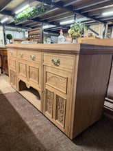 Load image into Gallery viewer, A striking satinwood sideboard, stripped to reveal its natural grain and warm patina. This substantial piece shows authentic character with minor surface marks befitting its vintage heritage. The stripped finish offers flexibility—a protective wax coat will enhance the wood and deepen its lustre. Generously proportioned storage comprises two short dovetail-jointed drawers and one long drawer above two single cupboards and a shorter double cupboard. Ideal for dining rooms or living spaces where both display 
