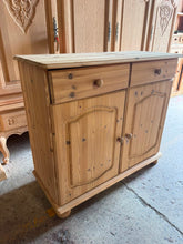Load image into Gallery viewer, A practical stripped pine sideboard in structurally sound condition. The natural wood finish showcases authentic grain and character, though a protective coat of wax is recommended to enhance durability. Generous storage comprises two short drawers positioned above a double cupboard with internal shelf—ideal for dining rooms, hallways, or living spaces requiring organised storage solutions.

Delivery Available

Overall Dimensions

89cm wide x 39cm deep x 79cm high

