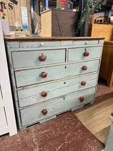 Load image into Gallery viewer, A characterful piece with genuine vintage appeal, this rustic oak chest combines practical storage with authentic period charm. The distressed finish and natural wear marks tell a story of years well-lived, whilst the solid construction ensures reliable everyday use. Five main drawers—two shallow and three deep—provide ample space, complemented by two concealed compartments at the top for treasured items. The blue-grey painted base contrasts beautifully with the warm oak surface. Minor imperfections, includ
