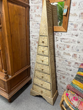 Load image into Gallery viewer, Discover the striking presence of this Mayan-inspired pyramid chest of drawers. Built to last, the piece is structurally sound and well-maintained, offering seven drawers for organising clothing or personal items. The geometric form and cultural aesthetic make it an ideal focal point for eclectic, bohemian, or contemporary interiors seeking character and depth. A conversation starter that doesn't compromise on function.

Delivery Available

Overall Dimensions

43cm wide x 22cm deep x 149cm high

