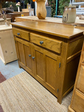 Load image into Gallery viewer, This sweet oak sideboard is structurally sound and in overall good condition. There are a few marks especially to the top but nothing too major at all. There are 2 dovetail jointed drawers for storage over a double cupboard with 1 shelf in for storage.

Overall Dimensions

107cm wide x 41cm deep x 84.5cm high 

DELIVERY AVAILABLE    

HAVE THIS PAINTED A COLOUR OF YOUR CHOICE FOR AN EXTRA £80 OR COMPLETELY STRIPPED BACK FOR £100 

For our other items see our website https://fossewayfurniture.co.uk

collecti
