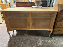 Load image into Gallery viewer, Stripped mahogany sideboard showcasing traditional joinery and solid construction. This vintage piece reveals beautiful bare wood grain after complete stripping, ready for your finishing touches. Two dovetail-jointed drawers sit above a spacious double cupboard with shelf storage—perfect for dining room essentials or display pieces. The frame remains structurally robust despite minor cosmetic marks that reflect its age. A wax finish will protect the wood and enhance its warm tones.

Delivery Available

Over

