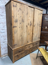 Load image into Gallery viewer, This very rustic wardrobe is structurally sound and in overall good condition. It does have some marks but with a good polish this would come up as good as new. It has ample storage with 1 long hanging rail over 3 short drawers and 2 long. This item can completely dismantle into panels for easier moving.

Overall Dimensions

168cm wide x 58cm deep x 209cm high

DELIVERY AVAILABLE    

HAVE THIS PAINTED A COLOUR OF YOUR CHOICE FOR AN EXTRA £100 OR COMPLETELY STRIPPED BACK FOR £125

For our other items see ou
