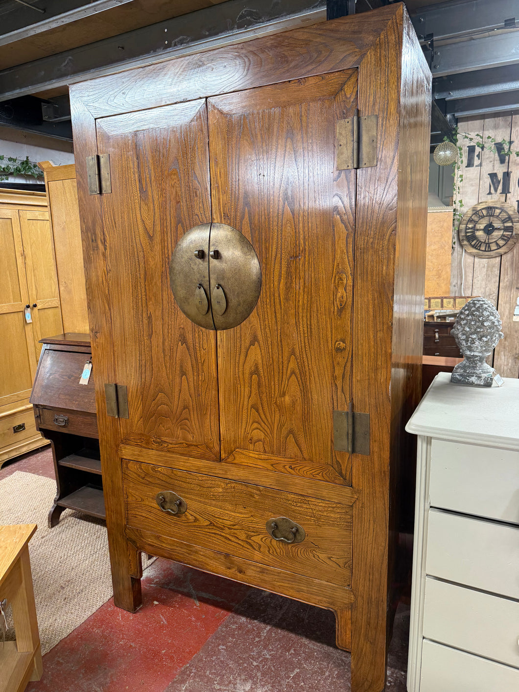 This durable, oriental-inspired wardrobe boasts a sturdy, solid wood construction and is in great condition overall. While there are some minor markings due to previous use, it is still very well-maintained. It features one hanging rail and a removable, adjustable shelf inside, as well as a discreetly placed hole in the back for wires (this was put in by previous owners). One of the legs has a small amount of damage, but it does not impact functionality.

Overall Dimensions

115cm wide x 58cm deep x 207cm h