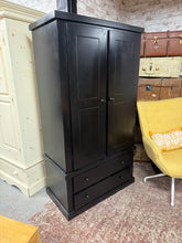 Load image into Gallery viewer, A sleek black pine wardrobe combining practical storage with contemporary style. Structurally sound and well-maintained, featuring one hanging rail and two spacious drawers for organised clothing storage. Minor surface marks reflect its authentic character. Ideal for modern bedrooms seeking functional elegance without compromise.

Delivery Available

Overall Dimensions

99cm wide x 52.5cm deep x 181.5cm high

