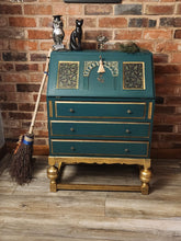 Load image into Gallery viewer, This gorgeous bureau, from around the 1940’s made from solid oak has been redesigned and refinished to create an absolutely stunning, unique piece of furniture.   This piece has been finished in Frenchic Victory Lane green and Plum Pudding paint. Trimmed with gorgeous gold, decoupaged with a forest bee design and golden bee handles.   Finally, the piece has been lacquered and waxed in high quality Frenchic for durability.  Overall Dimensions  Approx: Height 41cm, Width 29cm, Depth  
