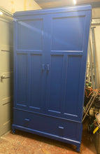 Load image into Gallery viewer, This stunning very quirky Tardis inspired wardrobe is structurally sound and in good condition. It has been painted in a deep blue. This wardrobe is divided into 2 single cupboards. one side has a shelf, a hanging rail and 2 hooks for storage. The other has 1 hanging rail , 2 hooks and a full length mirror. Both sit above 1 long dovetail jointed drawer.   Overall Dimensions  114cm wide x 50cm deep x 199cm high
